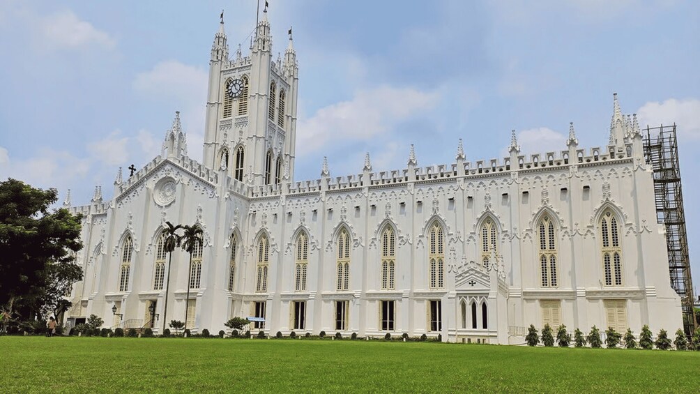 A large white Gothic-style cathedral with a clock tower, surrounded by a well-maintained lawn. 3