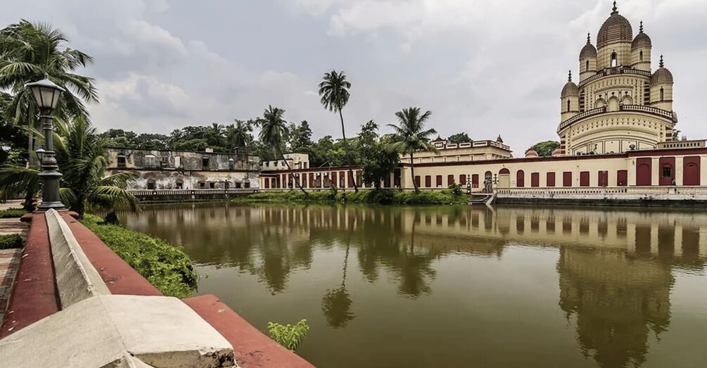 A calm river with a reflection of a large temple and surrounding greenery. 5