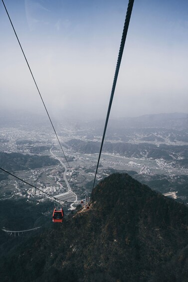 A cable car ascending a mountain with a cityscape in the background. 2