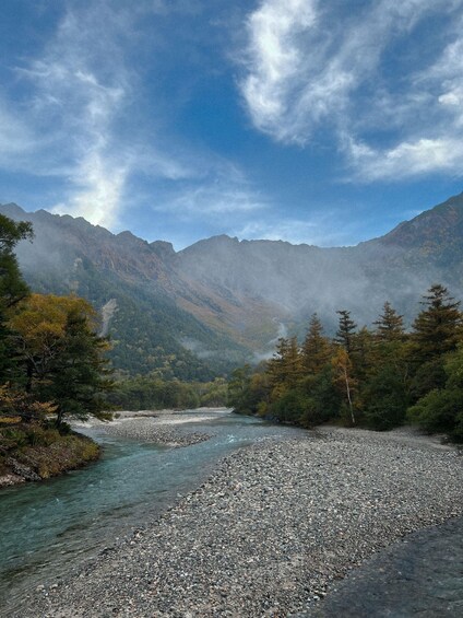 A river flowing through a mountainous landscape with rocky banks and dense forests. 4