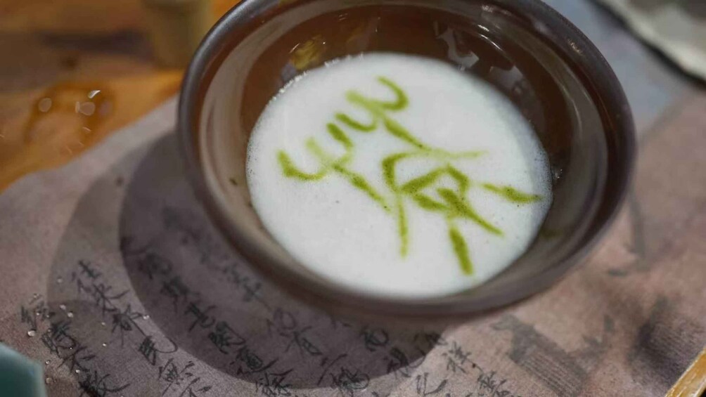 A bowl of white liquid with green writing on a cloth with Asian characters. 3
