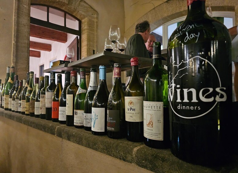 A row of wine bottles on a shelf with labels, in a restaurant setting. 2