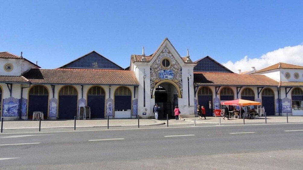 A historic building with a tiled roof and ornate facade, featuring a central archway and multiple arched windows. 4