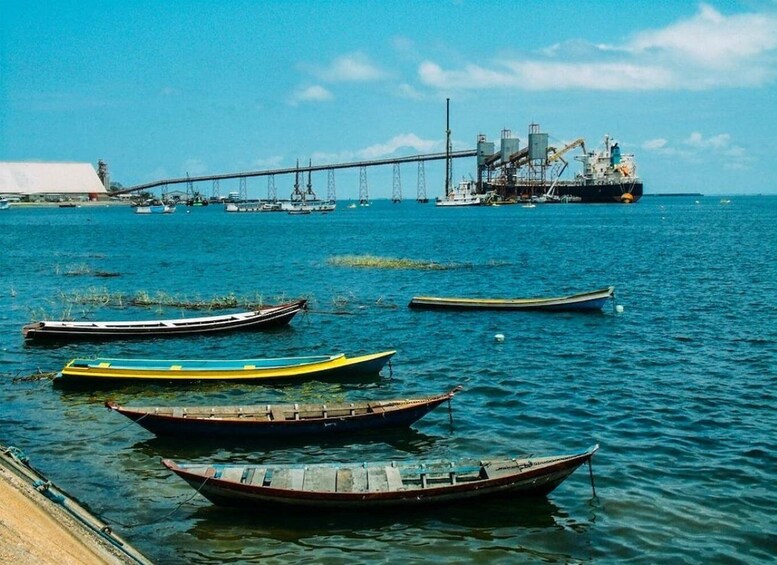 A harbor with several small boats, a large cargo ship, and a bridge in the background. 2