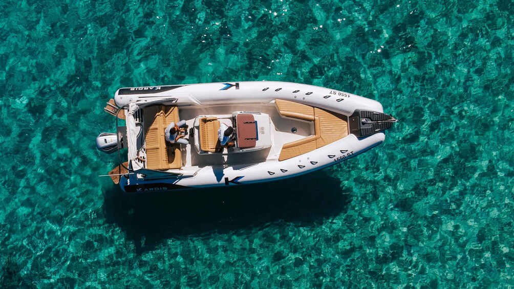 A white and brown motorboat named Kardis on clear turquoise water. 5