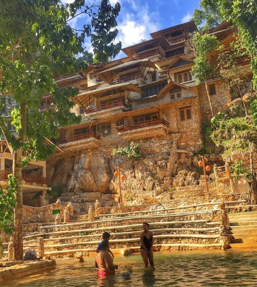 A traditional stone building with multiple balconies and a water feature in front. 4