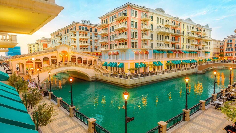 A canal with a bridge, buildings, and outdoor seating areas. 3