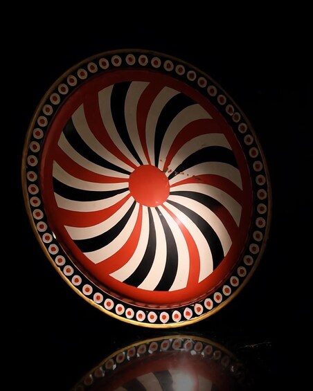 A circular object with concentric red and black stripes and a reflective surface. 5