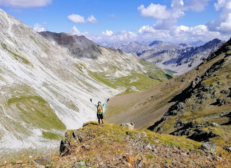 A hiker on a mountain ridge with snow patches and rocky terrain. 5