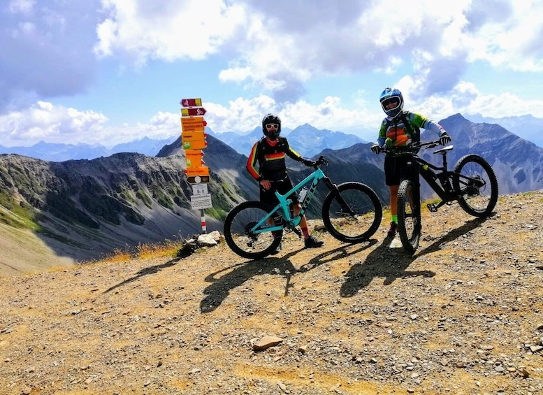 Two mountain bikers on a rocky trail with a trail sign in the background. 4