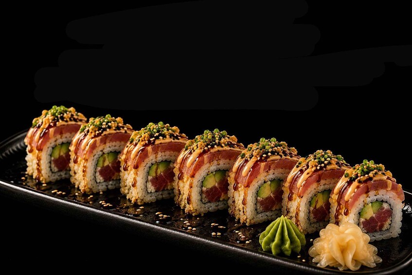 Sushi rolls with avocado, salmon, and sesame seeds on a black plate. 4