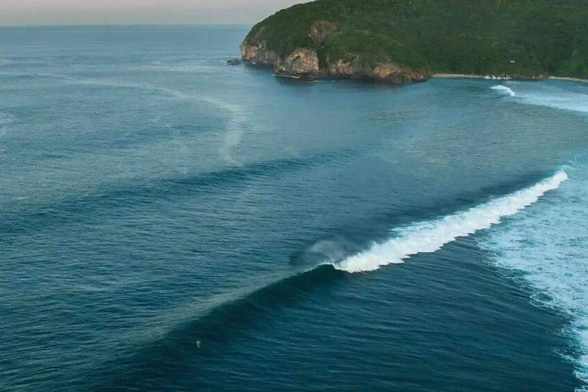 A large body of water with a wave breaking near a rocky coastline. 4