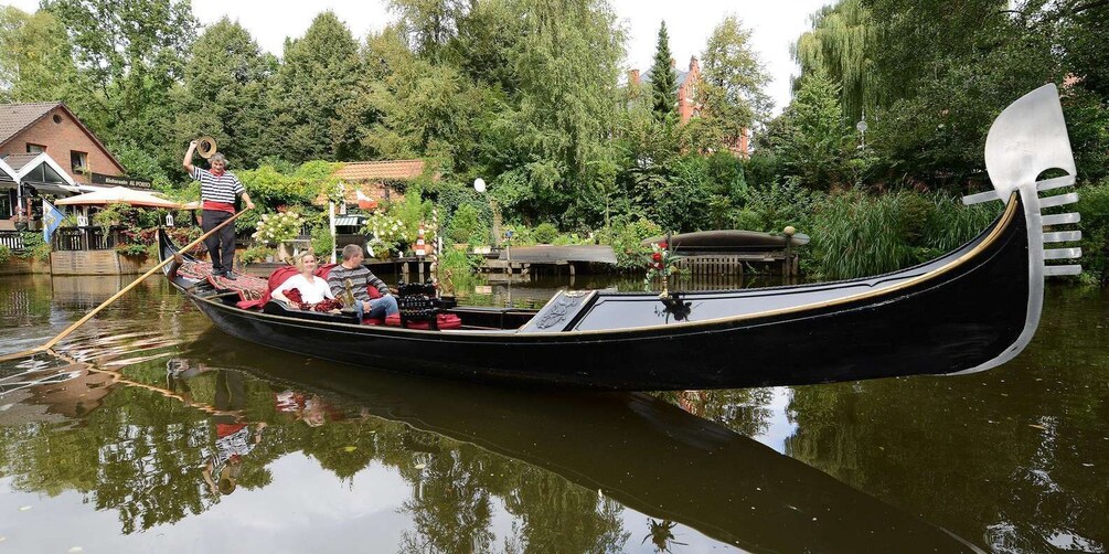 A gondola on a calm river, surrounded by lush greenery and a building with a sign reading 'Al Porto.' 1