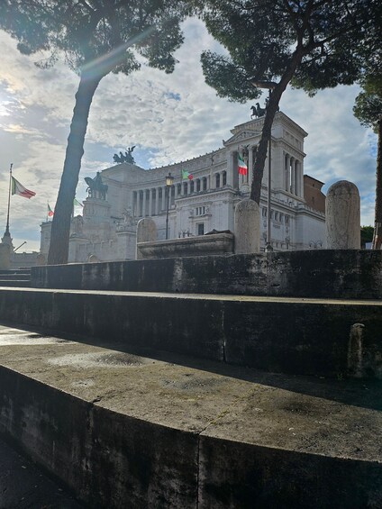 A classical building with columns, statues, and flags. 3