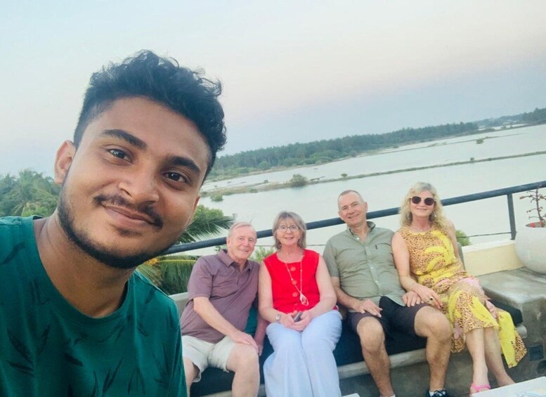 A group of people sitting on a bench by a river. 1