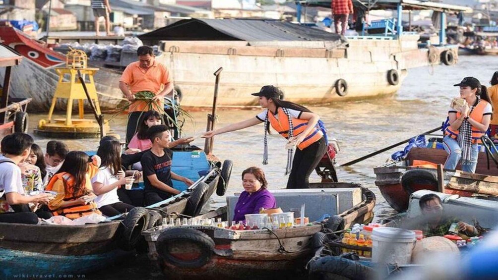 A group of people on boats, some wearing life jackets, with a woman in a purple shirt standing on a boat. 3