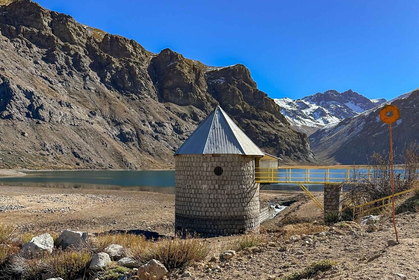 A stone structure near a lake with mountains in the background and a yellow bridge. 2
