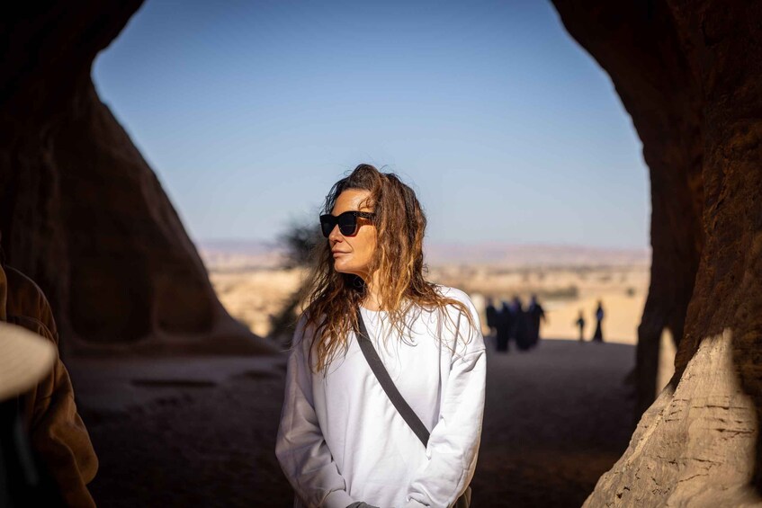 A person standing in a natural rock formation with a clear sky in the background. 1