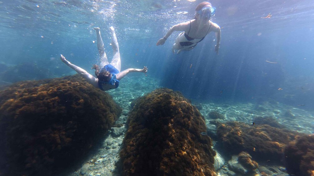 Two people snorkeling near large underwater rocks. 3