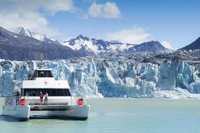 A boat in front of a glacier with passengers. 5