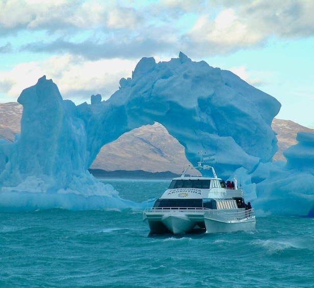 A boat named 'Patagonia Argentina' navigating through icy waters with a large ice arch formation in the background. 1