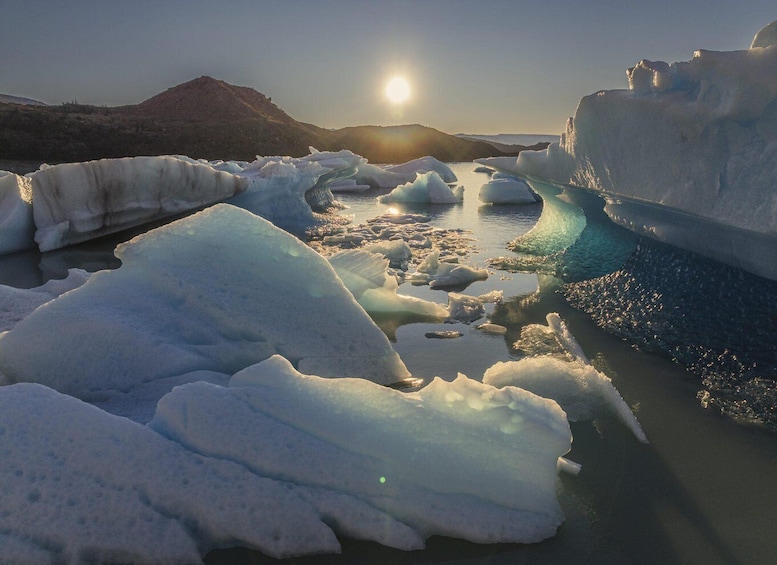 A frozen landscape with large icebergs and a calm body of water under a clear sky. 4