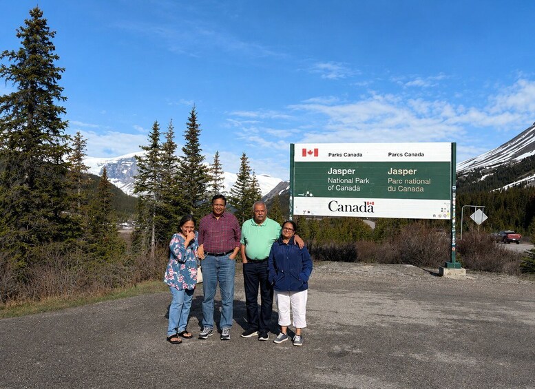 A family standing in front of a sign for Jasper National Park in Canada. 1