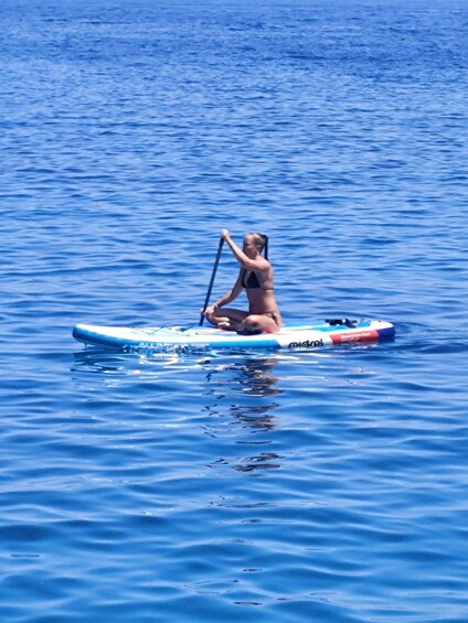 A person paddleboarding on a calm body of water. 3