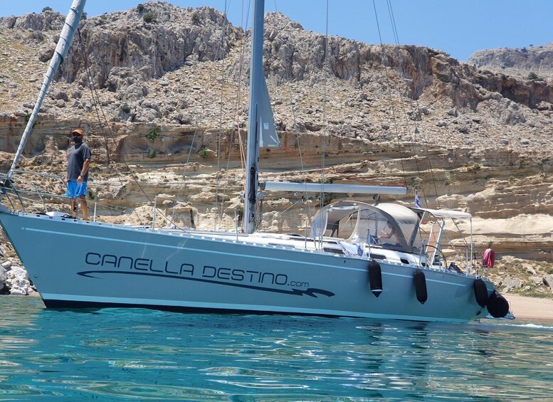 A sailboat named 'CANELLA DESTINO' docked near rocky cliffs. 2