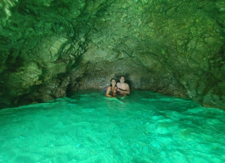 Two people in a cave with clear turquoise water. 4