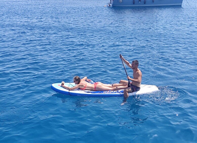 Two people on a paddleboard in the water with a boat in the background. 5