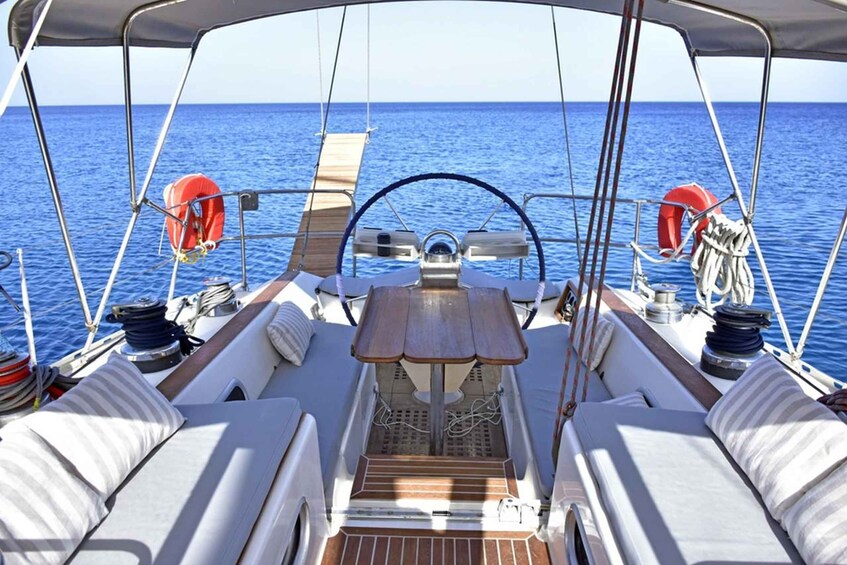 A sailboat's deck with a steering wheel, cushions, and life rings. 4