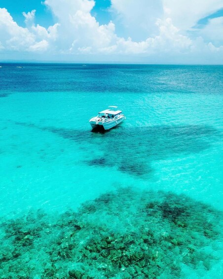 A boat on clear turquoise water with a coral reef in the foreground. 3
