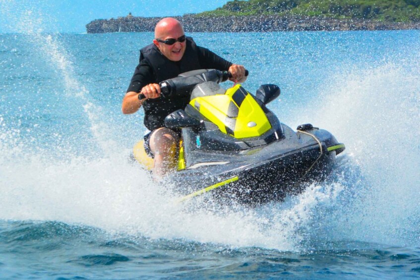 A person riding a yellow and black jet ski on water. 3
