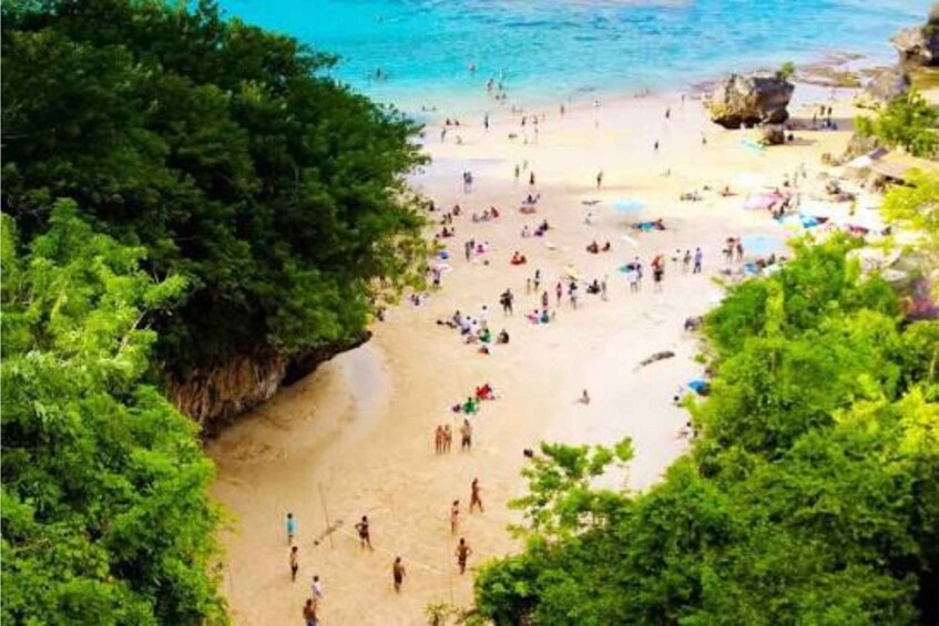 A beach with people sunbathing and swimming, surrounded by lush greenery and rocky formations. 4