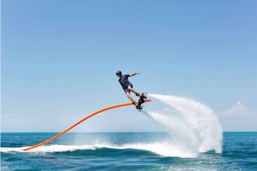 A person wakeboarding on a clear day over a body of water. 1