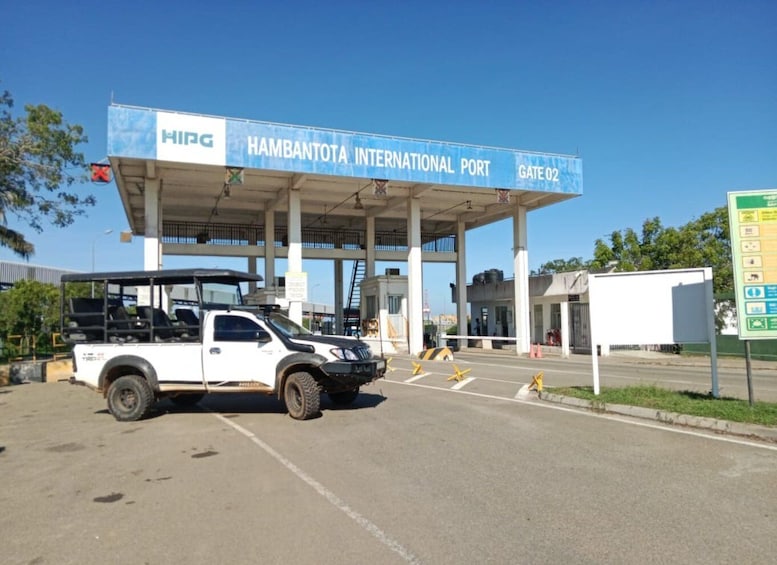 A white pickup truck parked at the entrance of HAMBANTOTA INTERNATIONAL PORT, Gate 02. 1