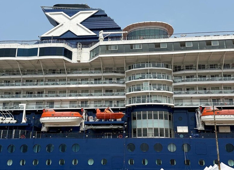 A large cruise ship with multiple decks and a prominent 'X' logo on the upper deck. 5