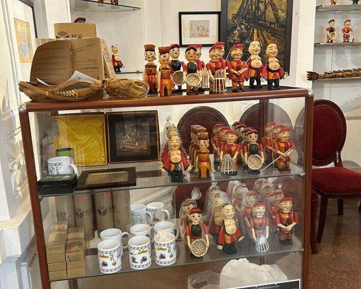 A display of traditional figures and ceramic mugs on shelves. 2