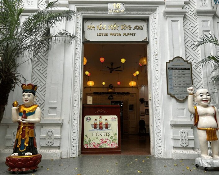 A building entrance with a sign for 'Lotus Water Puppet' and ticket booth. 5