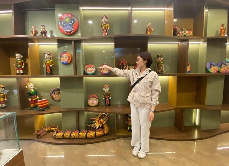 A person pointing at a display of cultural artifacts, including figures and a dragon. 1