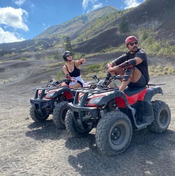 Two people on ATVs in a desert landscape with mountains in the background. 1