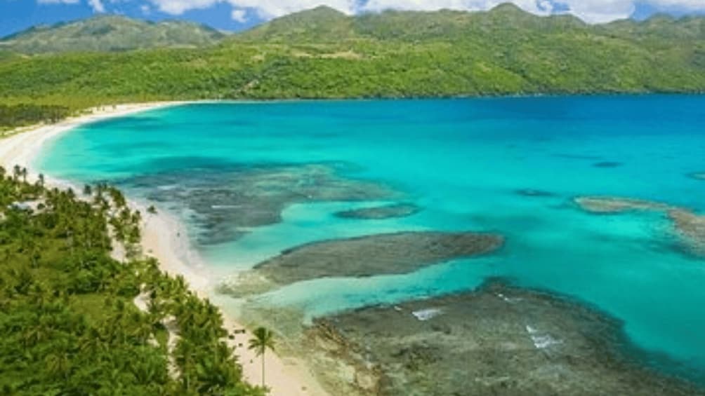 A tropical beach with clear turquoise waters and lush greenery. 1