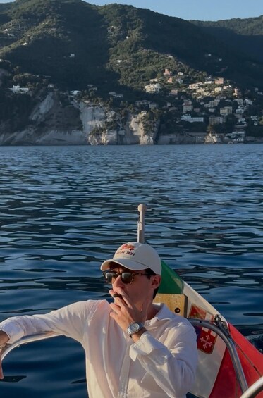 A person on a boat with a mountainous coastline in the background. 1