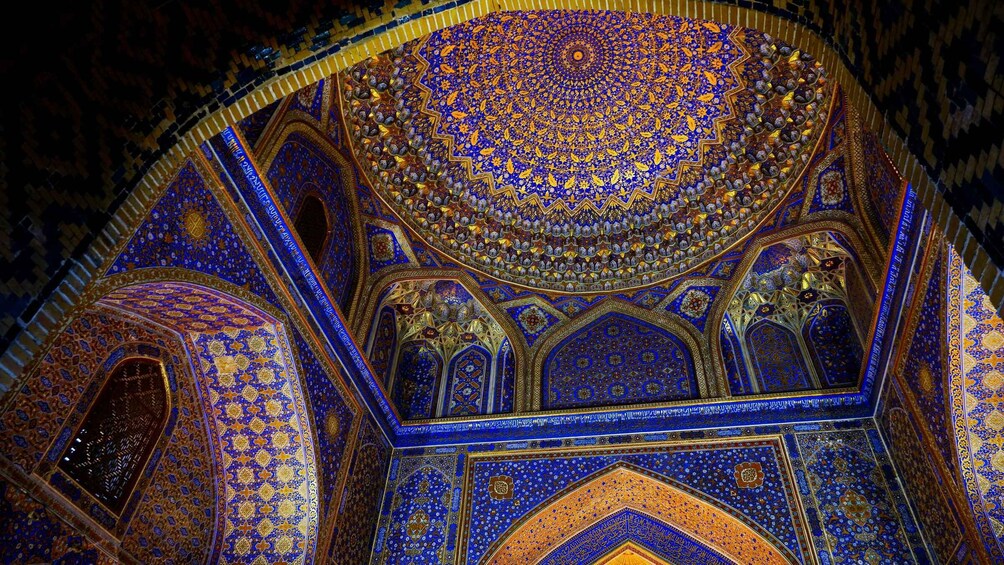 A detailed interior of a mosque with intricate blue and gold tile work, domes, and arches. 4