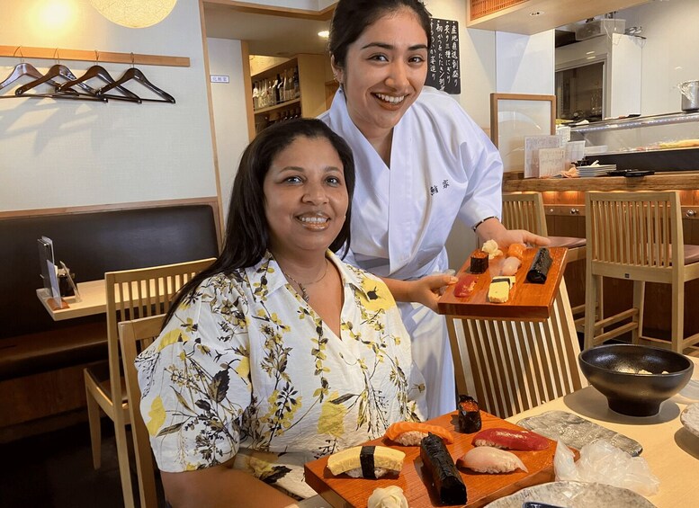 A restaurant interior with wooden furniture, a sushi display, and a person serving food. 2
