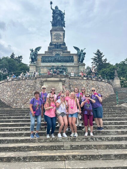 A group of people posing in front of a monument with statues and inscriptions. 2