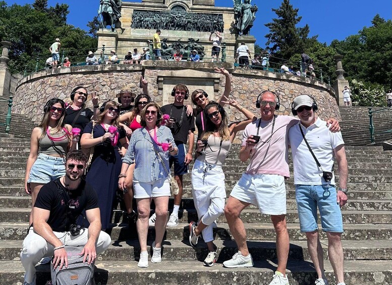 A group of people posing on stone steps with a statue and fountain in the background. 1