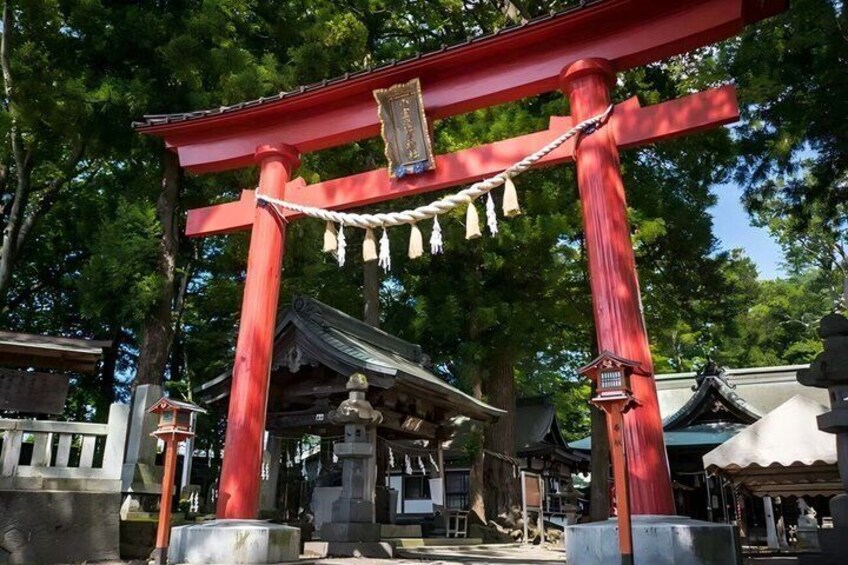 A traditional Japanese torii gate with a red frame, a shrine with a tiled roof, and a stone lantern. 4