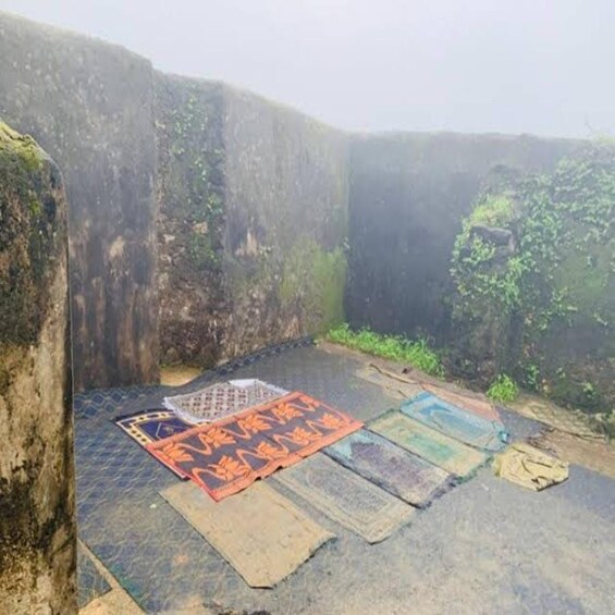 A stone wall with a patterned mat laid out on the ground. 3